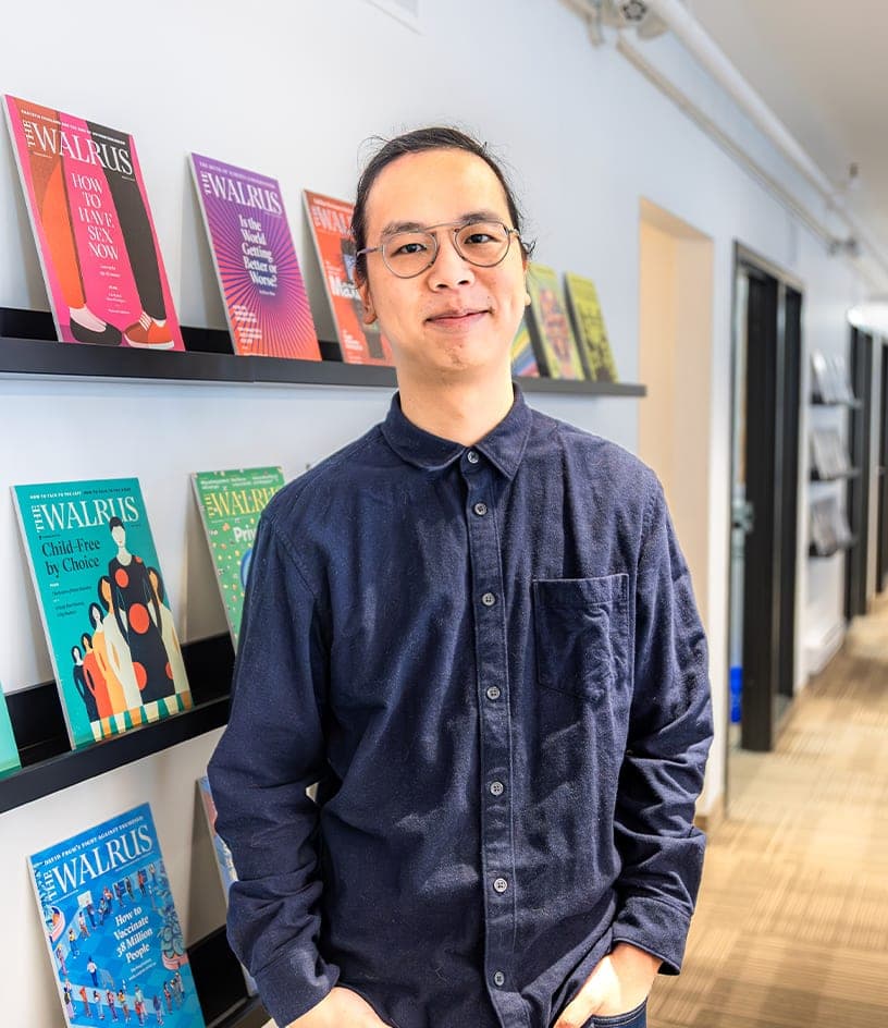 Portrait of Christopher Wang, Digital Director, with a magazine wall in the background