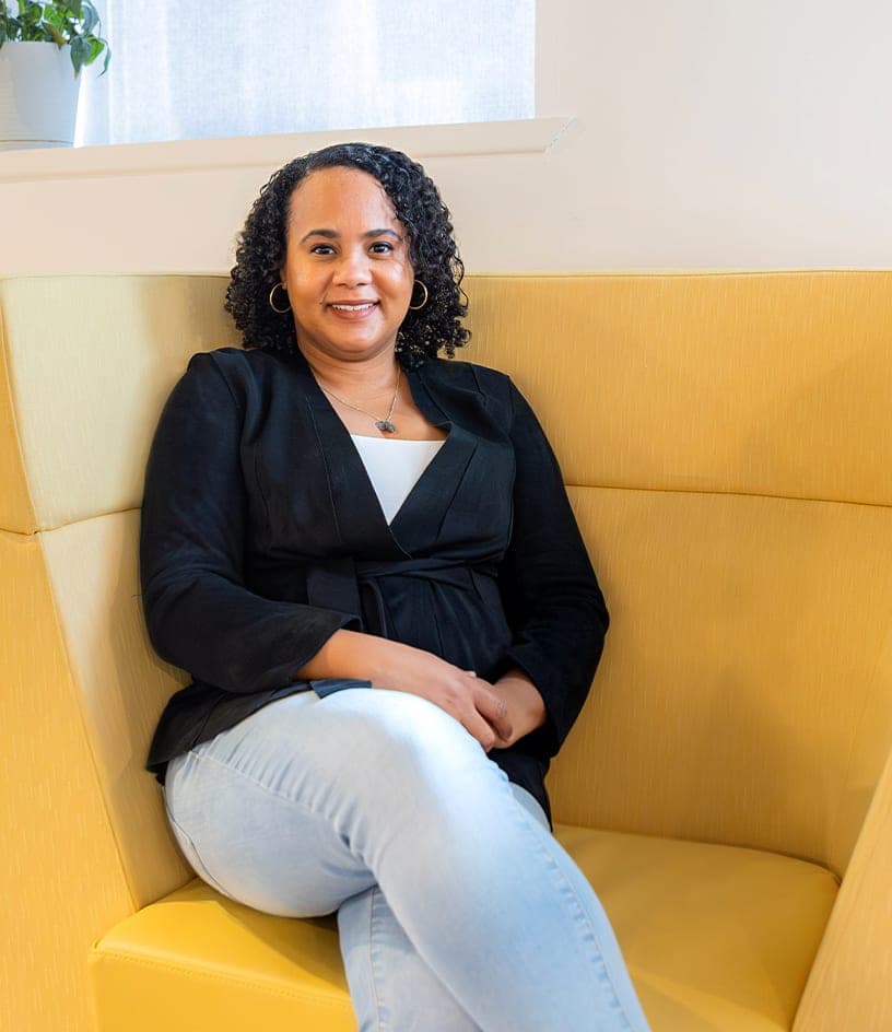 Portrait of Zoya Shepherd, Design Director, seated in a yellow armchair